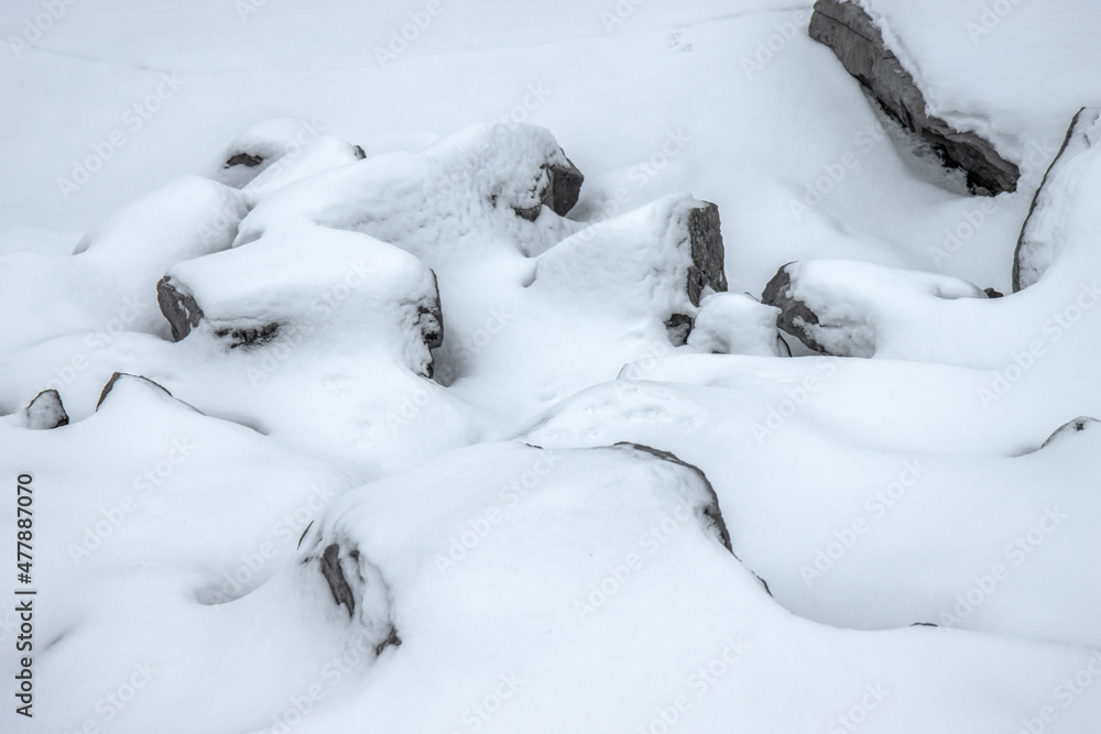 Grey boulders partially buried in deep snow