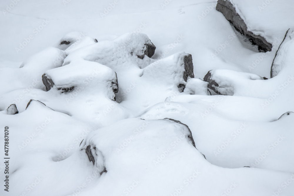 Grey boulders partially buried in deep snow Grey boulders partially buried in deep snow