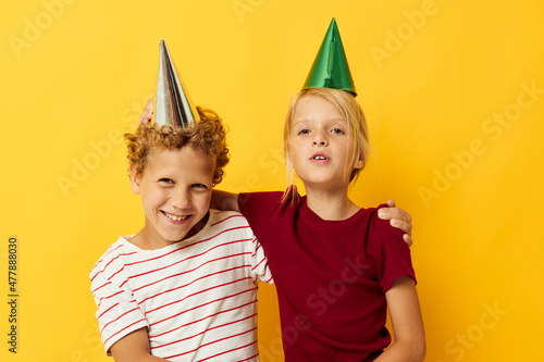 Portrait of cute children in casual clothes with caps on the head on colored background