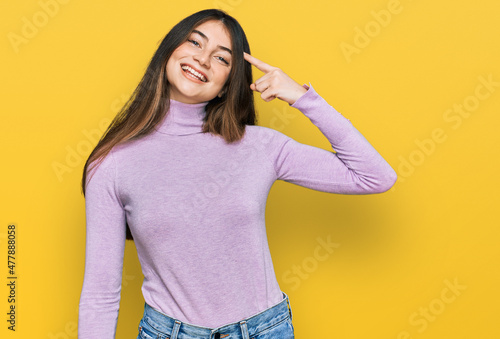 Young beautiful teen girl wearing turtleneck sweater smiling pointing to head with one finger, great idea or thought, good memory