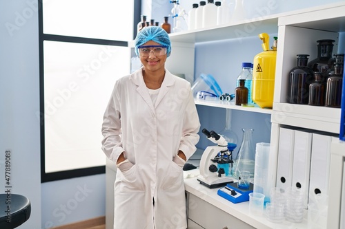 Young latin woman wearing scientist uniform standing at laboratory