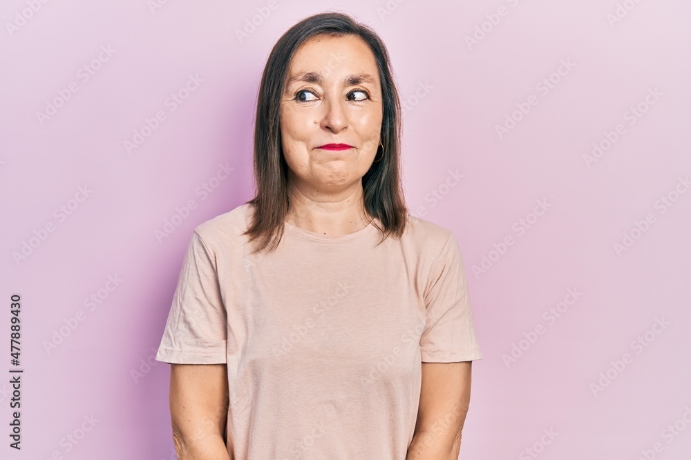 Middle age hispanic woman wearing casual clothes smiling looking to the side and staring away thinking. Middle age hispanic woman wearing casual clothes smiling looking to the side and staring away thinking.