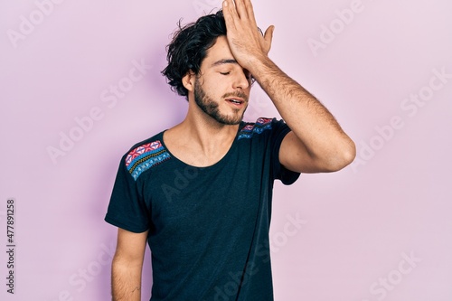 Konstfotografi Handsome hispanic man wearing casual t shirt surprised with hand on head for mistake, remember error