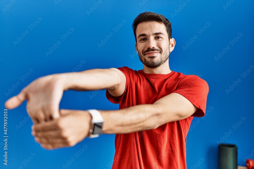 Young hispanic man smiling confident stretching at sport center Young hispanic man smiling confident stretching at sport center