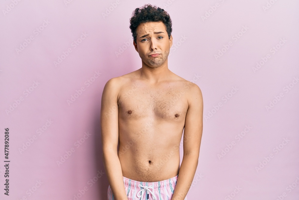 Fototapeta premium Young handsome man wearing swimwear shirtless depressed and worry for distress, crying angry and afraid. sad expression.