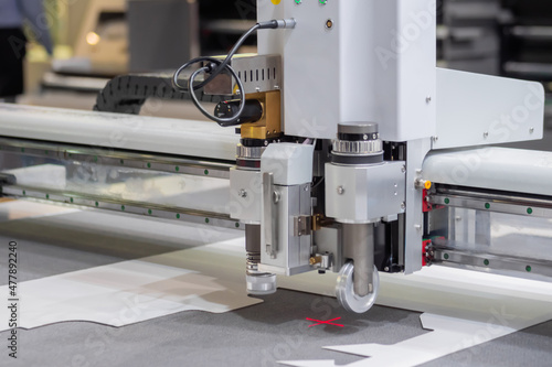 Photos Digital flatbed cutter, plotter cutting white cardboard sheet at printer exhibition, trade show - close up