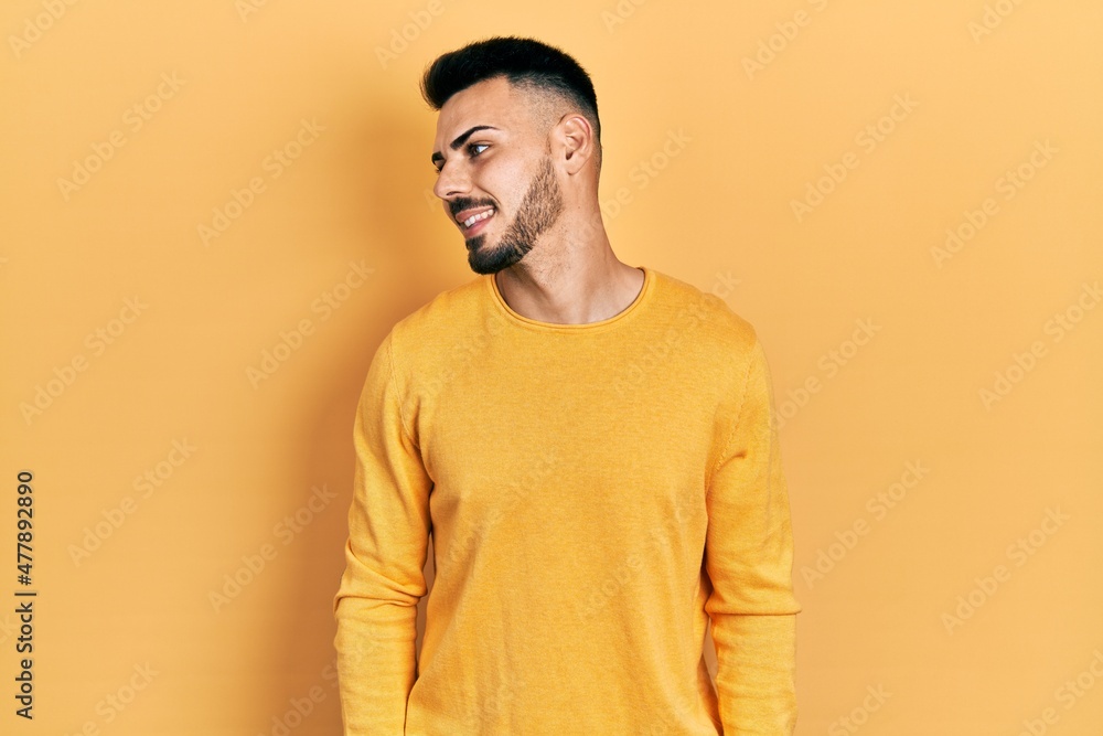Young hispanic man with beard wearing casual winter sweater looking to side, relax profile pose with natural face and confident smile. Young hispanic man with beard wearing casual winter sweater looking to side, relax profile pose with natural face and confident smile.