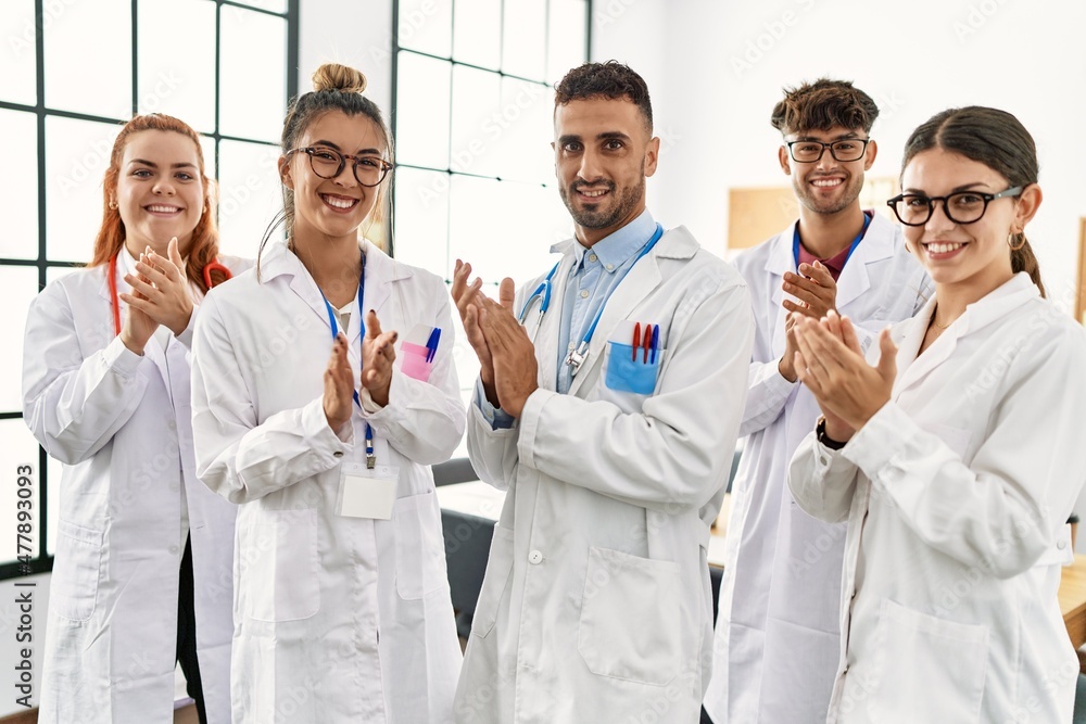 Group of young doctor smiling happy and clapping standing at the clinic office. Group of young doctor smiling happy and clapping standing at the clinic office.