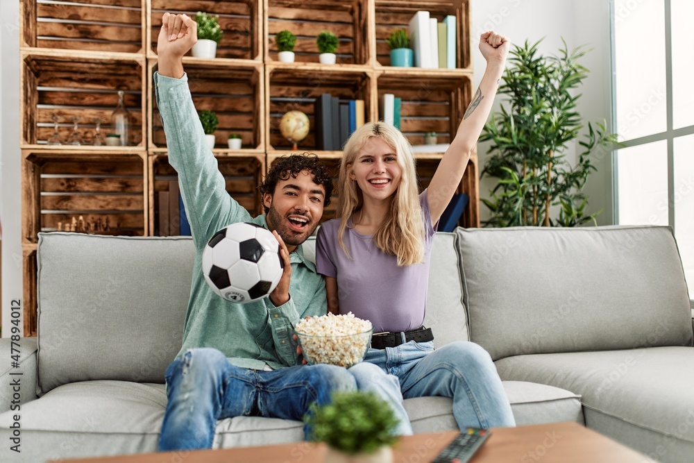 © Krakenimages.com - Young couple watching soccer match eating porpcorn at home.