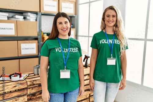 Two young volunteers woman smiling happy standing at charity center.