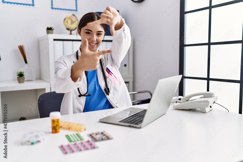 Young hispanic doctor woman wearing doctor uniform working at the clinic smiling making frame with hands and fingers with happy face. creativity and photography concept. Young hispanic doctor woman wearing doctor uniform working at the clinic smiling making frame with hands and fingers with happy face. creativity and photography concept.