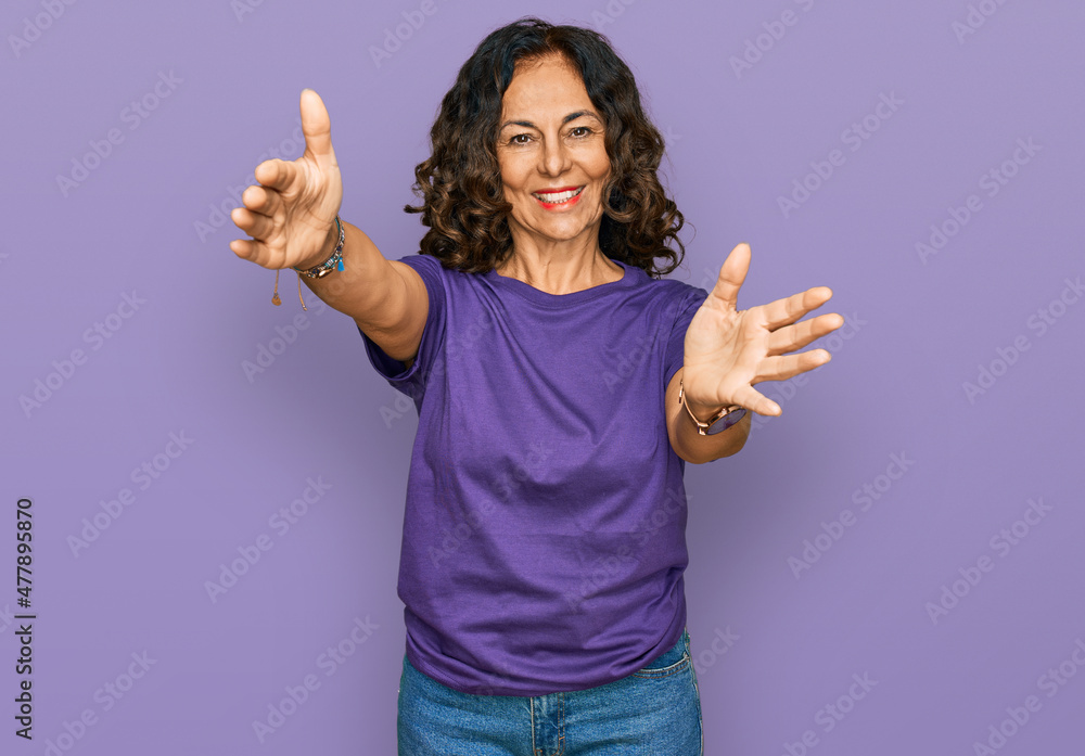 Middle age hispanic woman wearing casual clothes looking at the camera smiling with open arms for hug. cheerful expression embracing happiness.