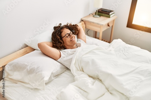 Middle age hispanic woman smiling confident wearing glasses at bedroom