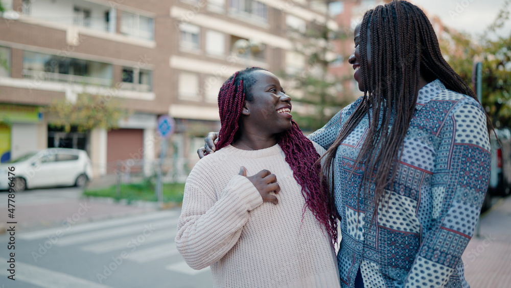 Fototapeta premium Two african american friends smiling confident hugging each other standing at street