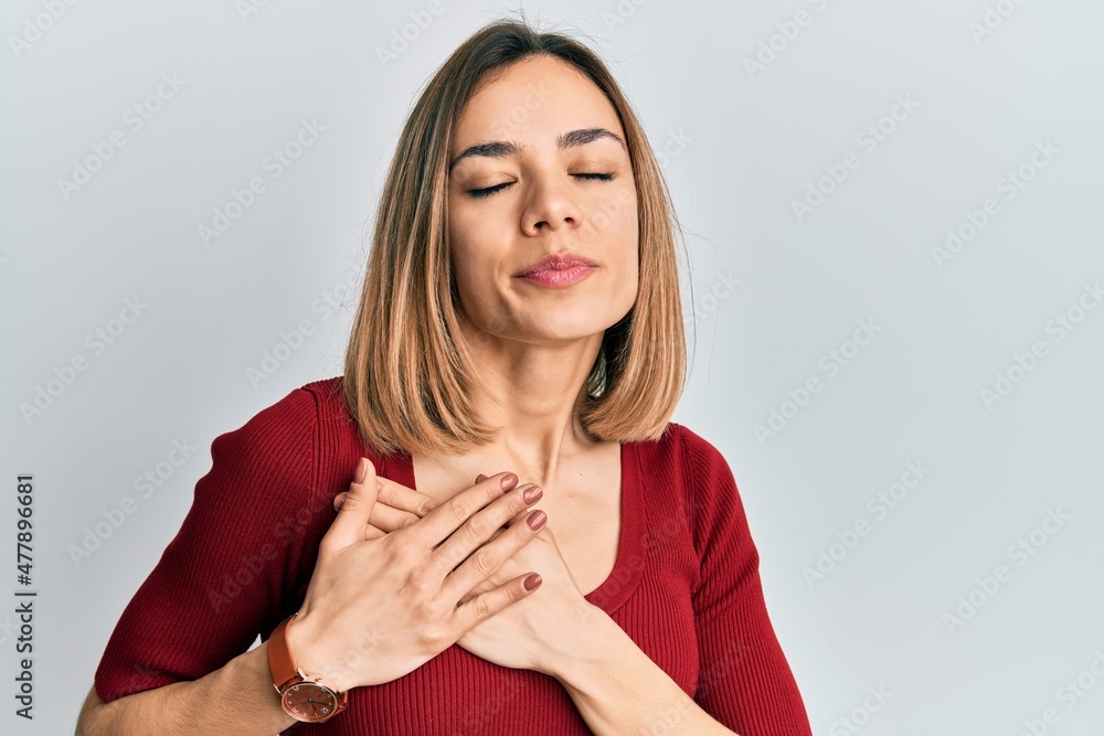 Young caucasian blonde woman wearing casual jumper smiling with hands on chest, eyes closed with grateful gesture on face. health concept. Young caucasian blonde woman wearing casual jumper smiling with hands on chest, eyes closed with grateful gesture on face. health concept.