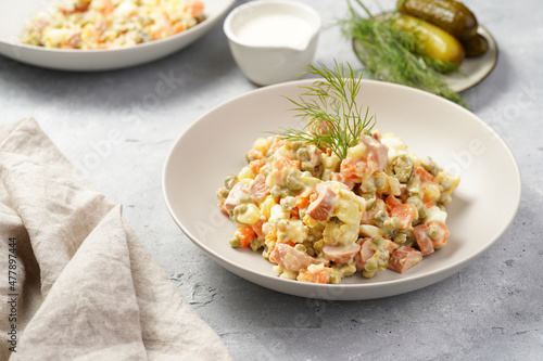 traditional east european dish for New Year's Eve - salad "Olivier" with potatoes, carrots, onion, peas, sausage, cucumbers, eggs and mayonnaise in a grey bowl
