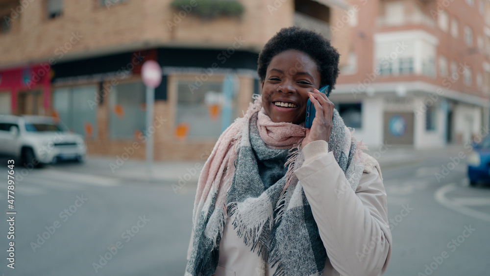 Fototapeta premium Young african american woman smiling confident talking on the smartphone at street