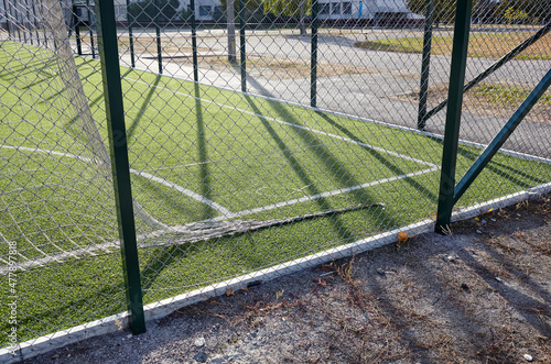 Lawn field for playing football behind the green fence mesh. Close-up of soccer field with green grass © supersomik
