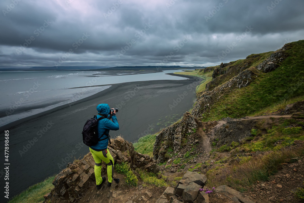 A tourist photographs a black beach on the Vatnsnes peninsula. Hvitserkur. Iceland