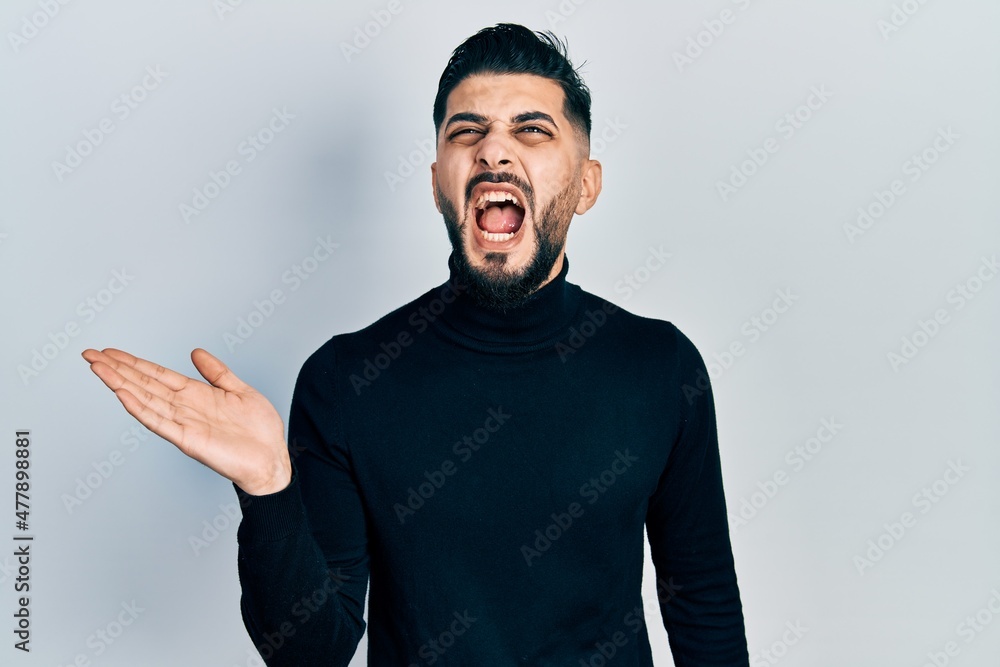 Handsome man with beard presenting with open palm angry and mad screaming frustrated and furious, shouting with anger looking up. Handsome man with beard presenting with open palm angry and mad screaming frustrated and furious, shouting with anger looking up.