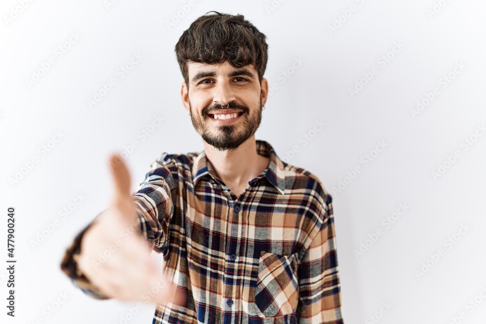 Hispanic man with beard standing over isolated background smiling friendly offering handshake as greeting and welcoming. successful business. Hispanic man with beard standing over isolated background smiling friendly offering handshake as greeting and welcoming. successful business.