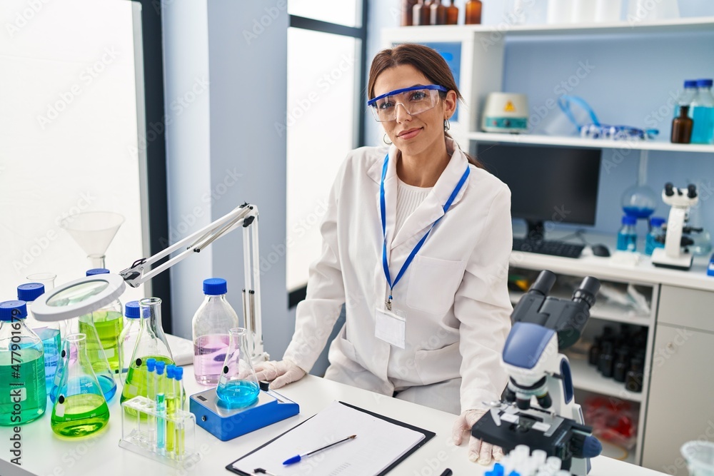 Young hispanic woman wearing scientist uniform standing at laboratory Young hispanic woman wearing scientist uniform standing at laboratory