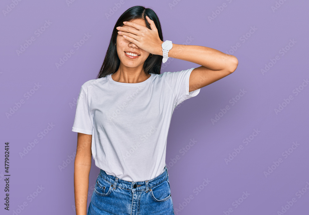 Beautiful young asian woman wearing casual white t shirt smiling and laughing with hand on face covering eyes for surprise. blind concept. Beautiful young asian woman wearing casual white t shirt smiling and laughing with hand on face covering eyes for surprise. blind concept.