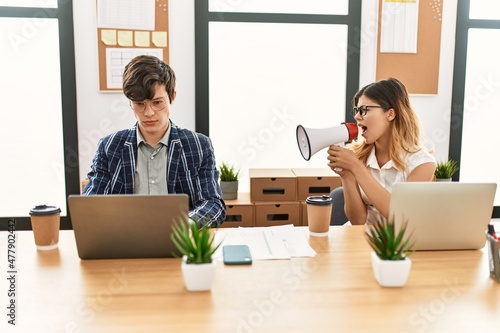 Businesswoman angry shouting her partner using megaphone at the office.