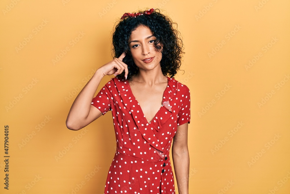 Young latin girl wearing summer dress smiling pointing to head with one finger, great idea or thought, good memory Young latin girl wearing summer dress smiling pointing to head with one finger, great idea or thought, good memory