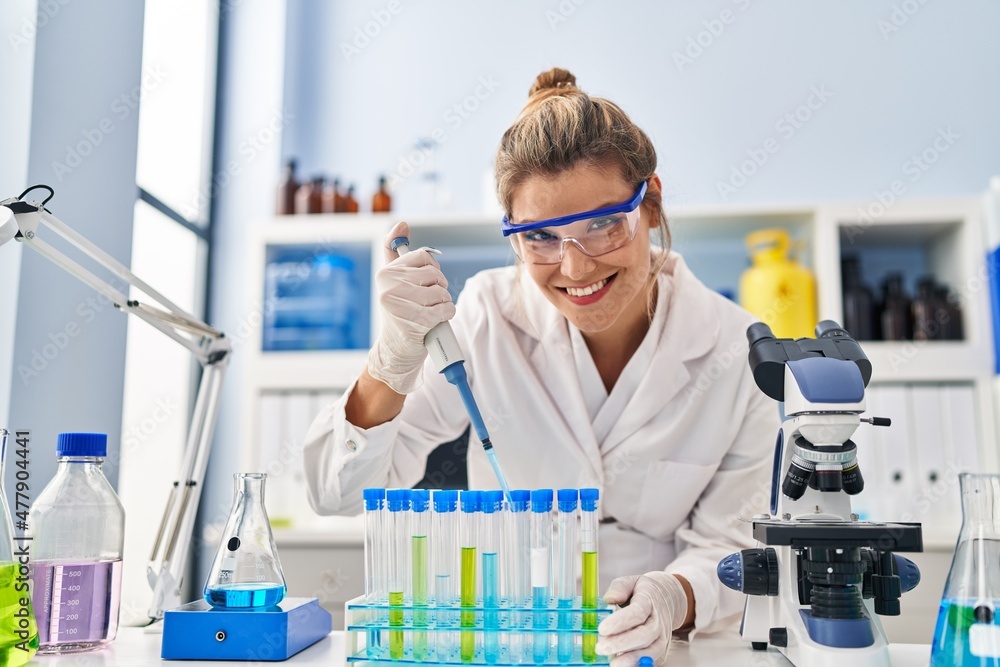 Young blonde woman wearing scientist uniform using pipette at laboratory Young blonde woman wearing scientist uniform using pipette at laboratory