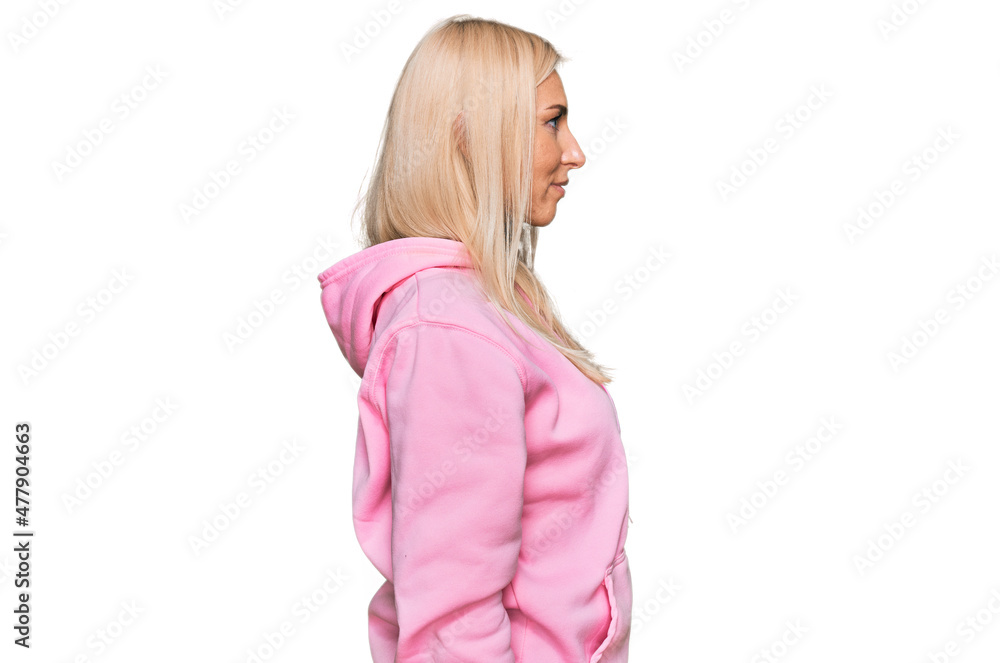 Young blonde woman wearing casual sweatshirt looking to side, relax profile pose with natural face and confident smile. Young blonde woman wearing casual sweatshirt looking to side, relax profile pose with natural face and confident smile.