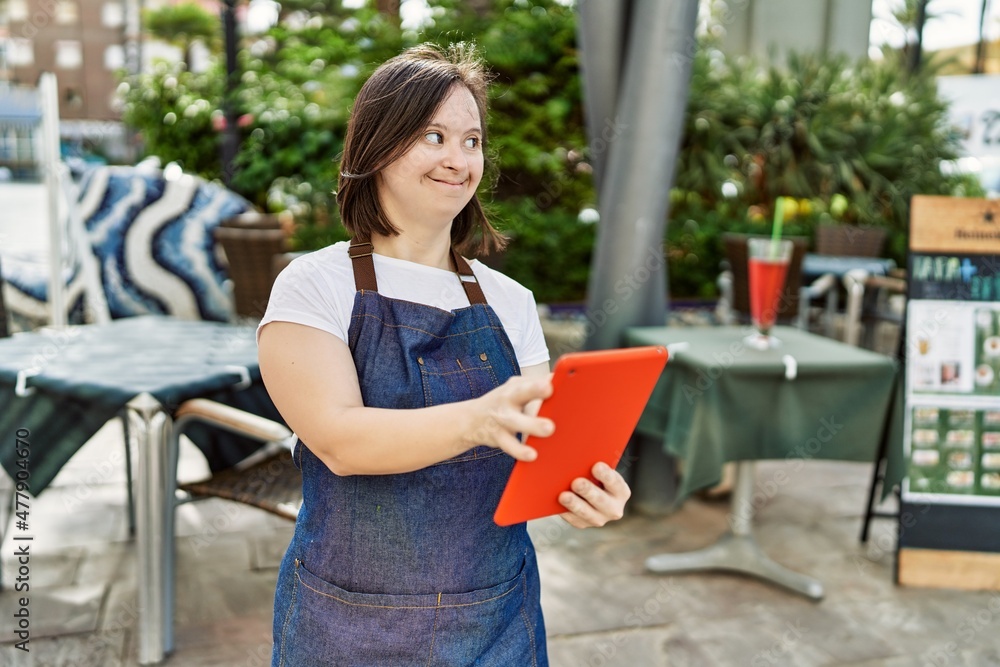 Young down syndrome woman wearing apron using touchpad at coffee shop terrace Young down syndrome woman wearing apron using touchpad at coffee shop terrace