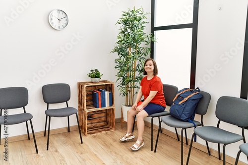 Brunette woman with down syndrome smiling sitting on chair at waiting room © Krakenimages.com