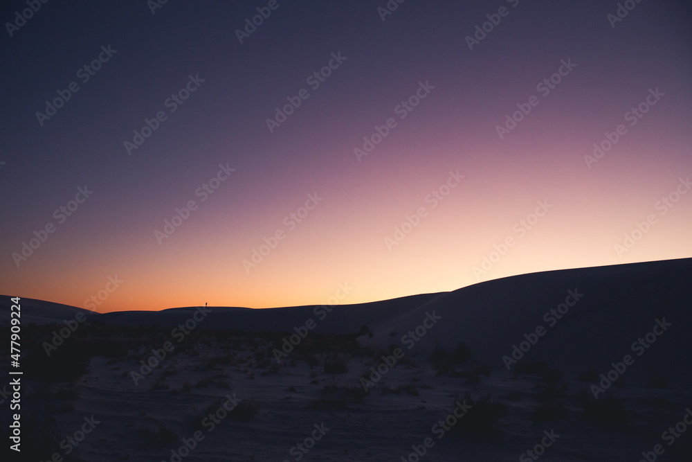 Hiker silhouette over sand dunes, 