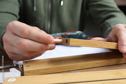 Man assembling wooden furniture at table, closeup