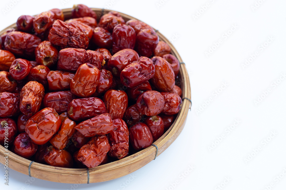 Dried Chinese jujubes in bamboo basket on white background.