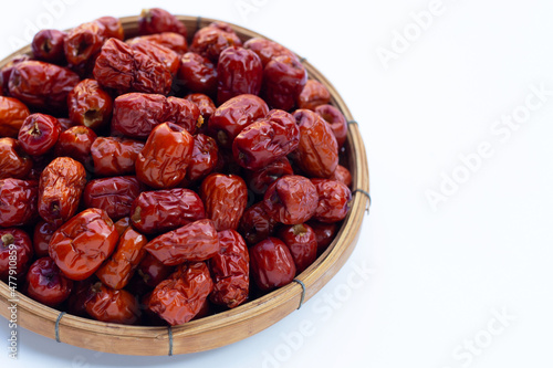 Dried Chinese jujubes in bamboo basket on white background.