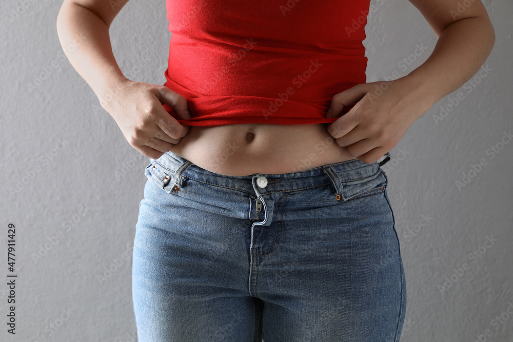 Foto de Woman wearing tight clothes on grey background, closeup. Overweight  problem do Stock