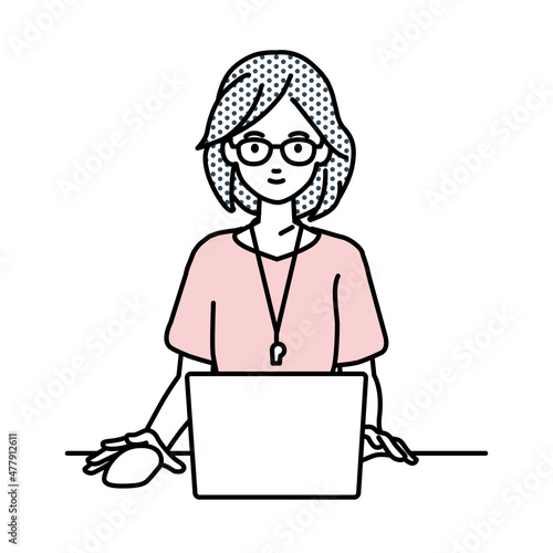 デスクで座ってPCを使っている教師の女性