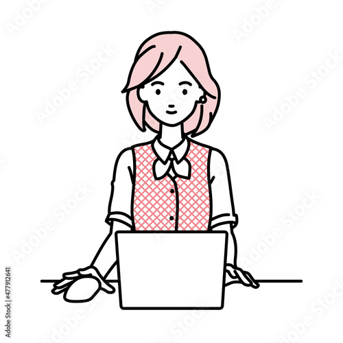 デスクで座ってPCを使っている事務員制服の女性