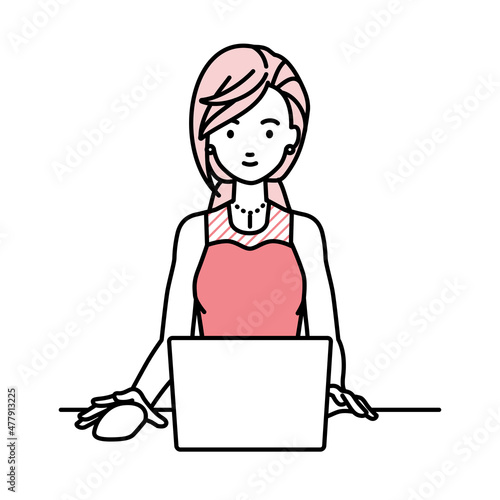 デスクで座ってPCを使っているドレスの女性