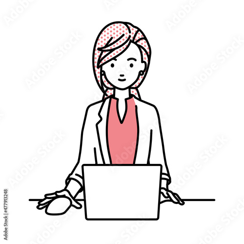 デスクで座ってPCを使っているジャケットの女性