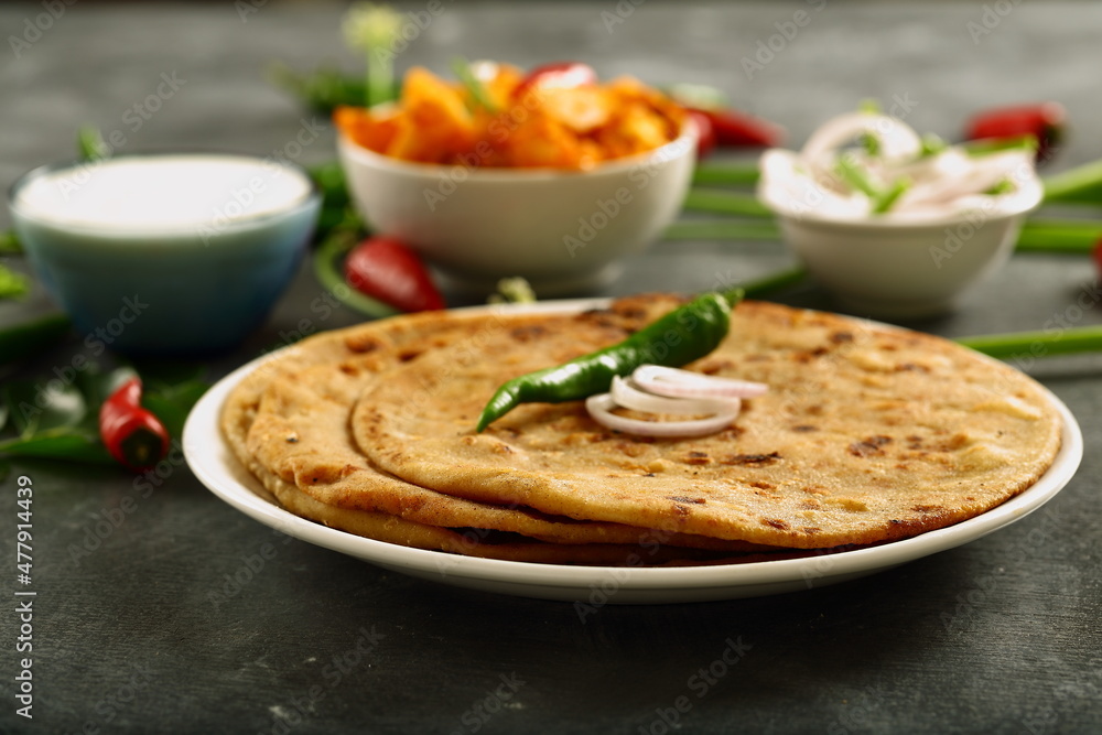`Indian street foods- aloo paratha served with potato curry and fresh raita.