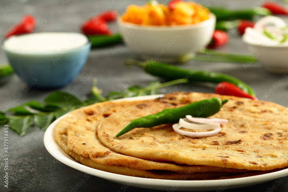 Indian vegetarian meal- healthy vegan diet - aloo paratha served with spicy potato curry and raita,. Indian vegetarian meal- healthy vegan diet - aloo paratha served with spicy potato curry and raita,.