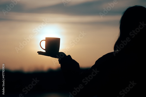 Silhouette of a Woman Holding a Coffee Mug in The Sunrise
