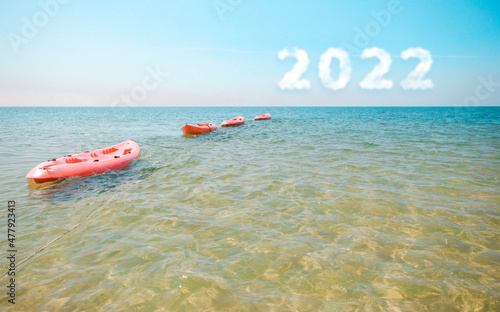 A bright Pink kayak on the sea
and 2022 in the sky. Concept Start new year 2022
