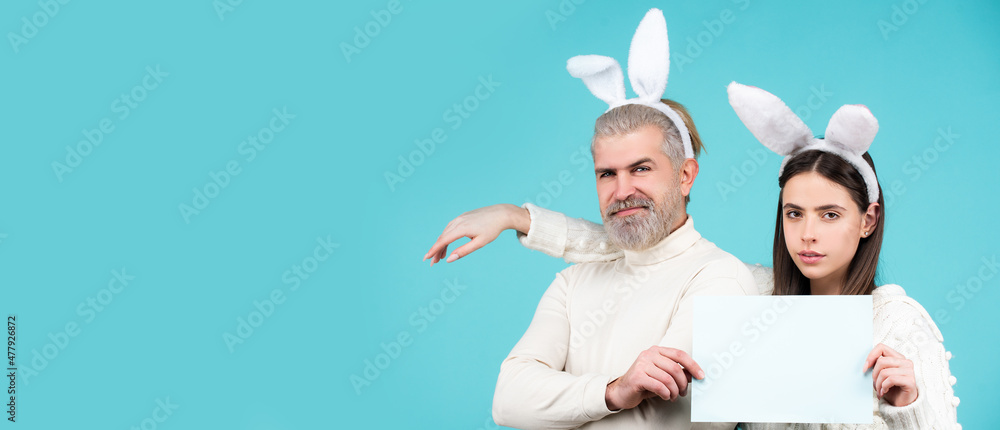 Easter bunny man and woman hold board board for text. Banner with funny bunny couple, copy space.