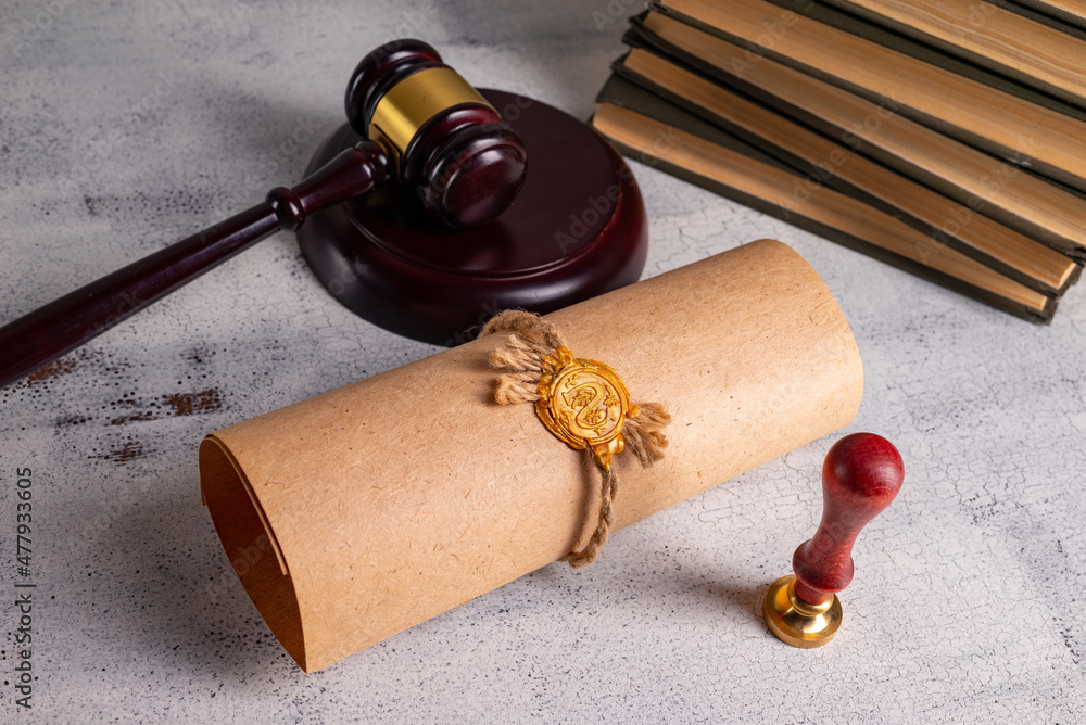 Judge's gavel, books, parchment scroll with seal and stamp on an old wooden table