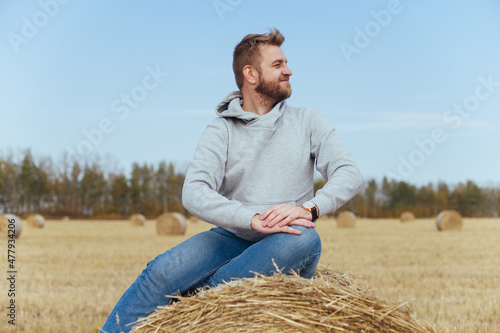 Happy man with a beard in a hoodie sits on a haystack © filins