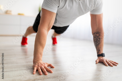 Closeup of mature male hands planking, wearing smartwatch while exercising in living room, crop